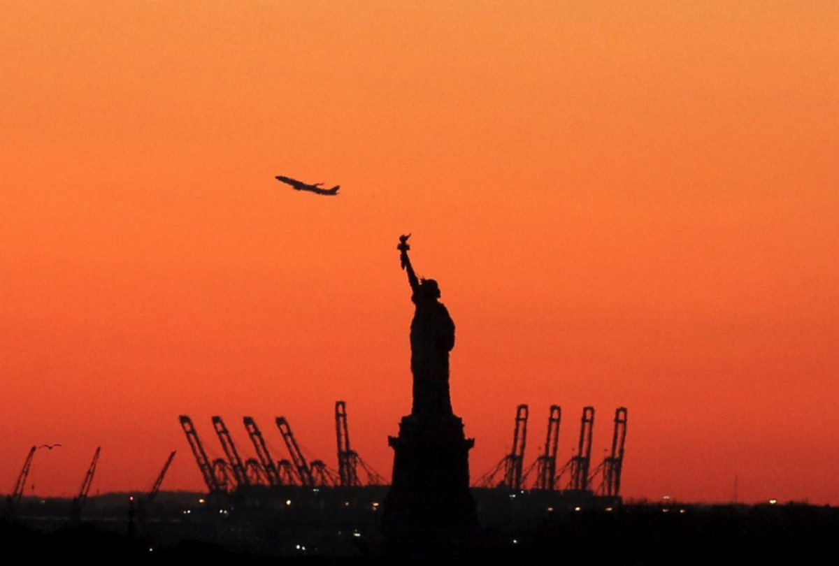 FILE PHOTO: A plane is seen during take off in New Jersey behind the Statue of Liberty in New York's Harbor as seen from the Brooklyn borough of New York February 20, 2016. REUTERS/Brendan McDermid/File Photo
