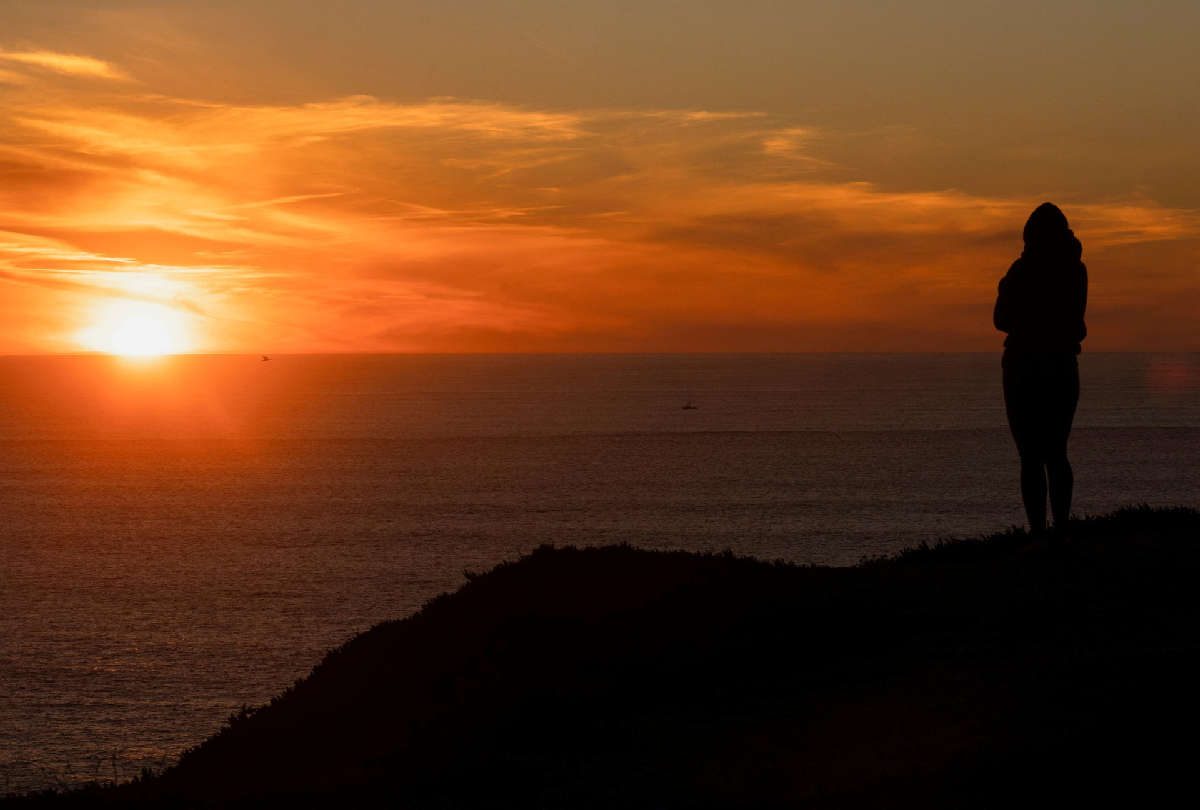 sunset woman looking at ocean 1200x810