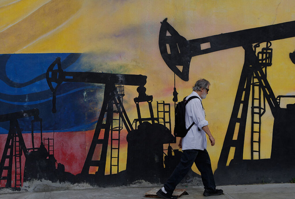 a pedestrian walks past a mural featuring oil wells in caracas, venezuela cp176824742 1200x810